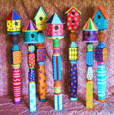 several colorful birdhouses are lined up against a wall