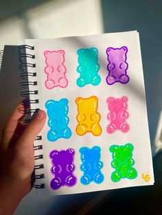 someone is holding up a notebook with colored bears on the pages and in front of them