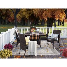 an outdoor dining set on a deck with fall foliage