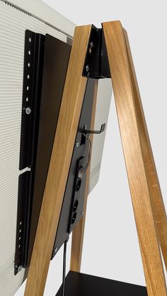 a close up of a monitor on a stand with a wooden frame and black hardware