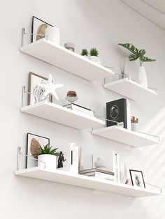 some white shelves with plants and pictures on them