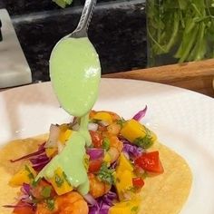 a taco filled with vegetables and sauce being drizzled on top of it