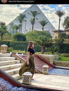 a woman is walking down some steps in front of a pyramid shaped building with palm trees