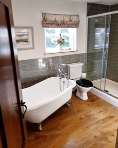 a white bath tub sitting inside of a bathroom next to a toilet under a window