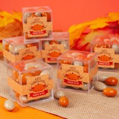 small clear boxes filled with candy sitting on top of a table next to autumn leaves