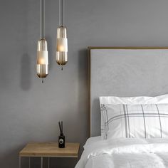 three lights hanging over a bed next to a night stand