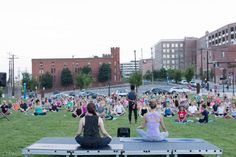 people are sitting in the grass and doing yoga