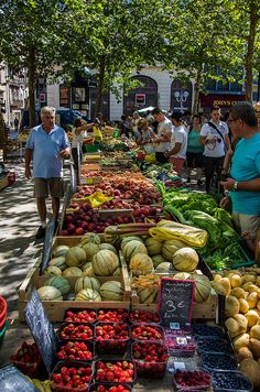 people shopping at an outdoor market with fruits and vegetables