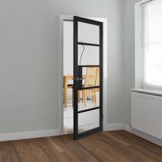 an empty room with a chair and table in the corner, viewed through a glass door