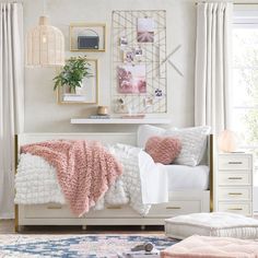 a bedroom with pink and white decor on the walls, rugs and bedding