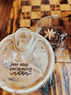 a glass bowl with writing on it sitting on top of a wooden table next to a plastic cup