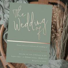 the wedding card is sitting on top of a wicker basket next to dried flowers