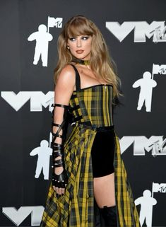 taylor swift at the vmas awards wearing a yellow and black plaid dress with thigh high boots