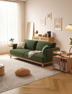 a living room with a green couch and coffee table next to a large open window