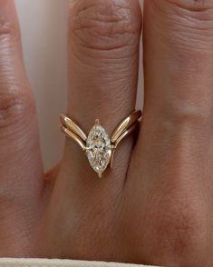 a woman's hand with a diamond ring on top of her finger and the other hand is holding an engagement ring