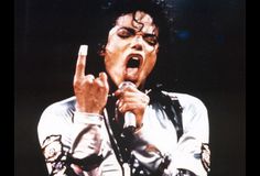 michael jackson singing into a microphone with his hands in the air and one finger up