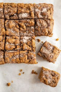 several pieces of brownie sitting on top of a piece of parchment paper with powdered sugar