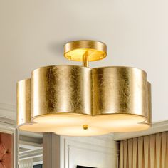 a light fixture hanging from the ceiling in a room with white walls and gold curtains