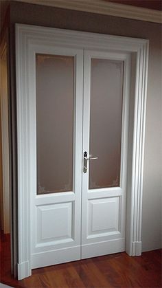 two white double doors with frosted glass on the top and bottom panels, in an empty room