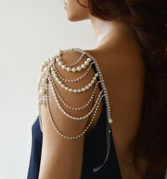 the back of a woman's shoulder with pearls and chains attached to her arm