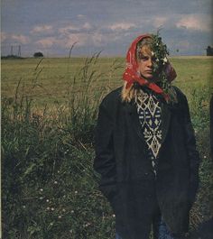 a man standing in a field wearing a red bandana on his head and looking at the camera