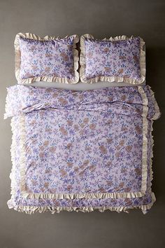 a bed with purple and blue floral bedspread, pillows and pillowcases