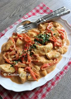 a white plate topped with pasta covered in sauce and garnished with herbs next to a fork