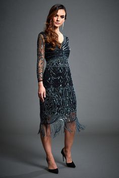 Guaranteed to be the life of the party in this stunning Gatsby-inspired flapper dress. The intricate embellished detail of the dress and mesh sleeves adds glitz and glam to this look whilst the scalloped hemline and fringed detail ensures youll be twirling on the dancefloor all night! V-neckline Roaring 20s Prom Dresses, 20s Prom Dress, Gatsby Inspired Dress, Art Deco Party, Fringe Flapper Dress, V Neck Cocktail Dress, Art Deco Dress, Long Sleeve Cocktail Dress, London Outfit