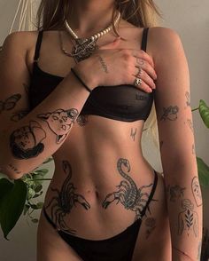 a woman with many tattoos on her body and hands behind her back, wearing a black bra