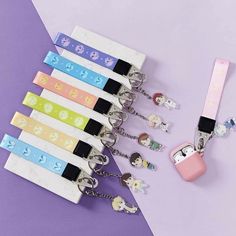 the key chains are attached to each other on a purple and white background with pastel colors