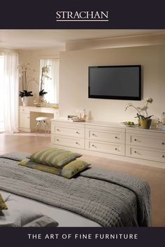 a bedroom with white furniture and a flat screen tv mounted on the wall above it