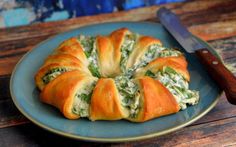 a pastry with spinach and cheese is on a blue plate next to a knife