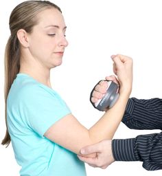 a woman holding an object in her right hand while another person holds it up to the other