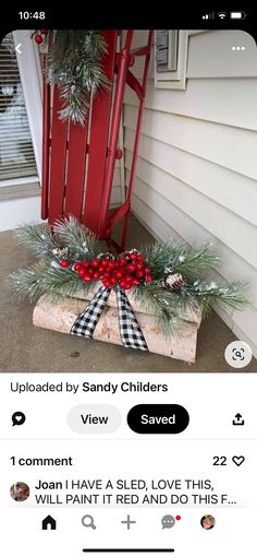 a red rocking chair sitting on top of a porch next to a christmas wreath and pine cones