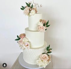 a three tiered white wedding cake with pink flowers on the top and green leaves