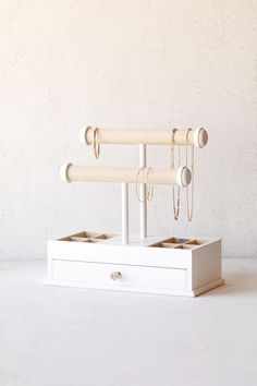 a white jewelry box with three necklaces and two earrings hanging from it's sides