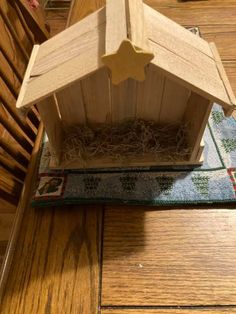 a wooden birdhouse with a star on the top sitting on a rug next to a chair