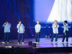 group of young men standing on stage with microphones