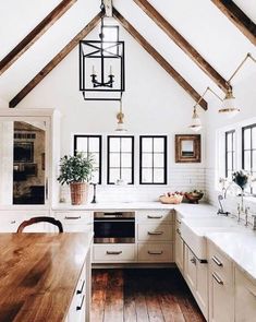 an open kitchen with white cabinets and wooden flooring is featured in this image, while the ceiling has exposed beams