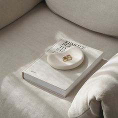 a book with two wedding rings on it sitting on a couch next to a pillow