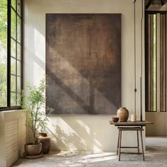 a large painting hanging on the wall next to a table with two potted plants