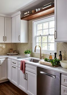 a clean kitchen with white cabinets and stainless steel dishwasher on the countertop