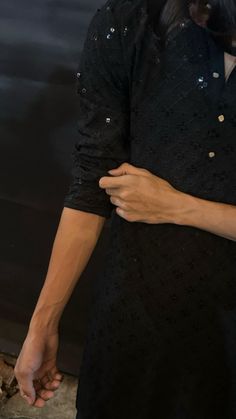 a woman holding the hand of a man who is wearing a black shirt and tie