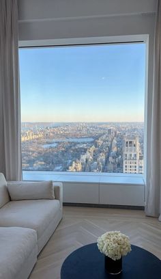 a living room filled with furniture and a large window overlooking a cityscape in the distance