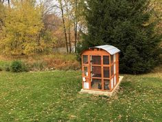 an outhouse in the middle of a field with trees and grass around it,