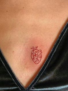 a small heart tattoo on the back of a woman's chest is seen in this image