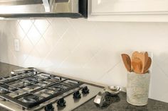 a stove top oven sitting inside of a kitchen next to a wooden utensil holder