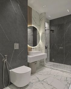 a modern bathroom with marble walls and flooring, along with a large round mirror on the wall