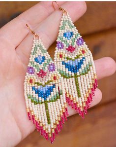 a pair of beaded earrings is being held in someone's hand with it