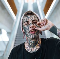 a man with lots of tattoos on his face and neck is making a funny face